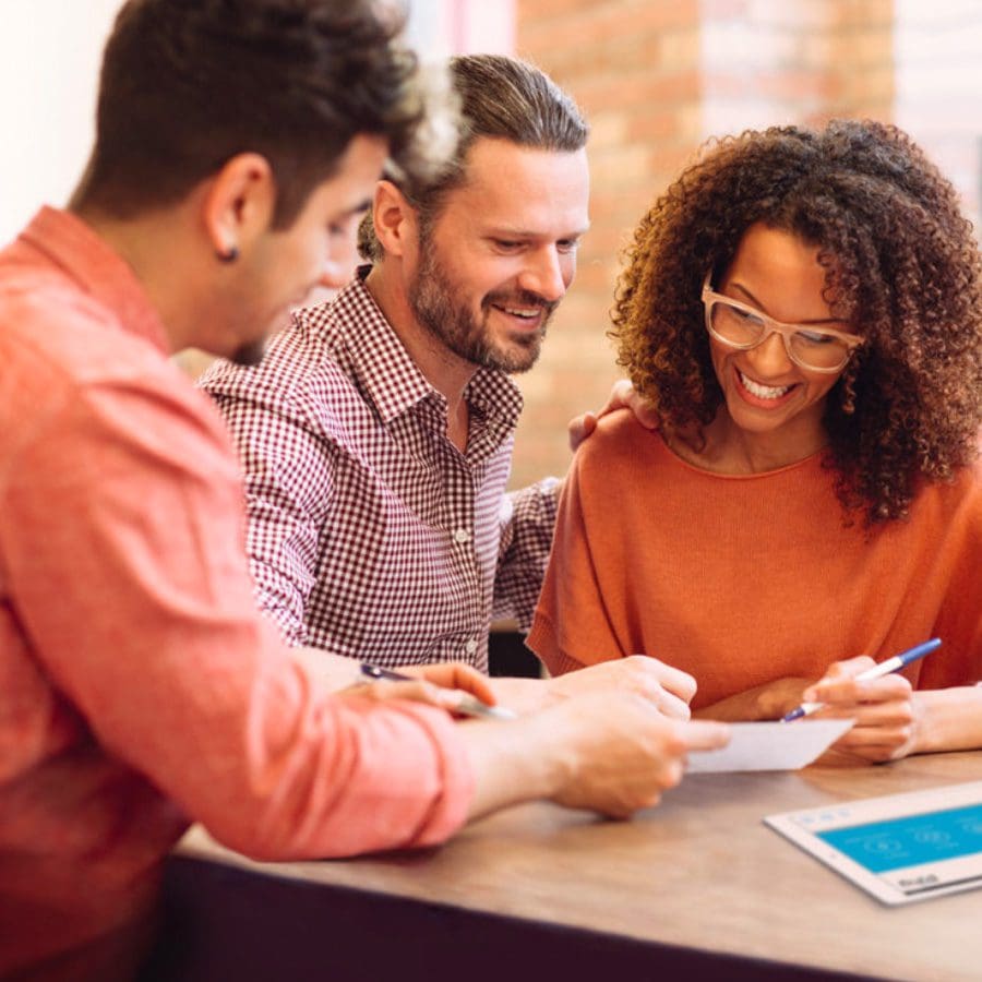 Three people review documents.