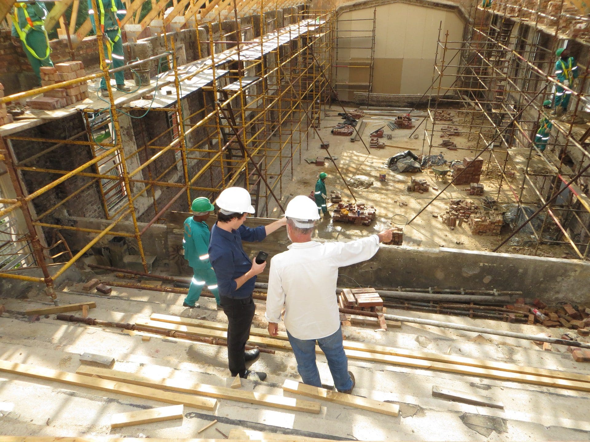 Men in hard hats view construction site.